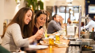 two girls sitting in a pub with beers